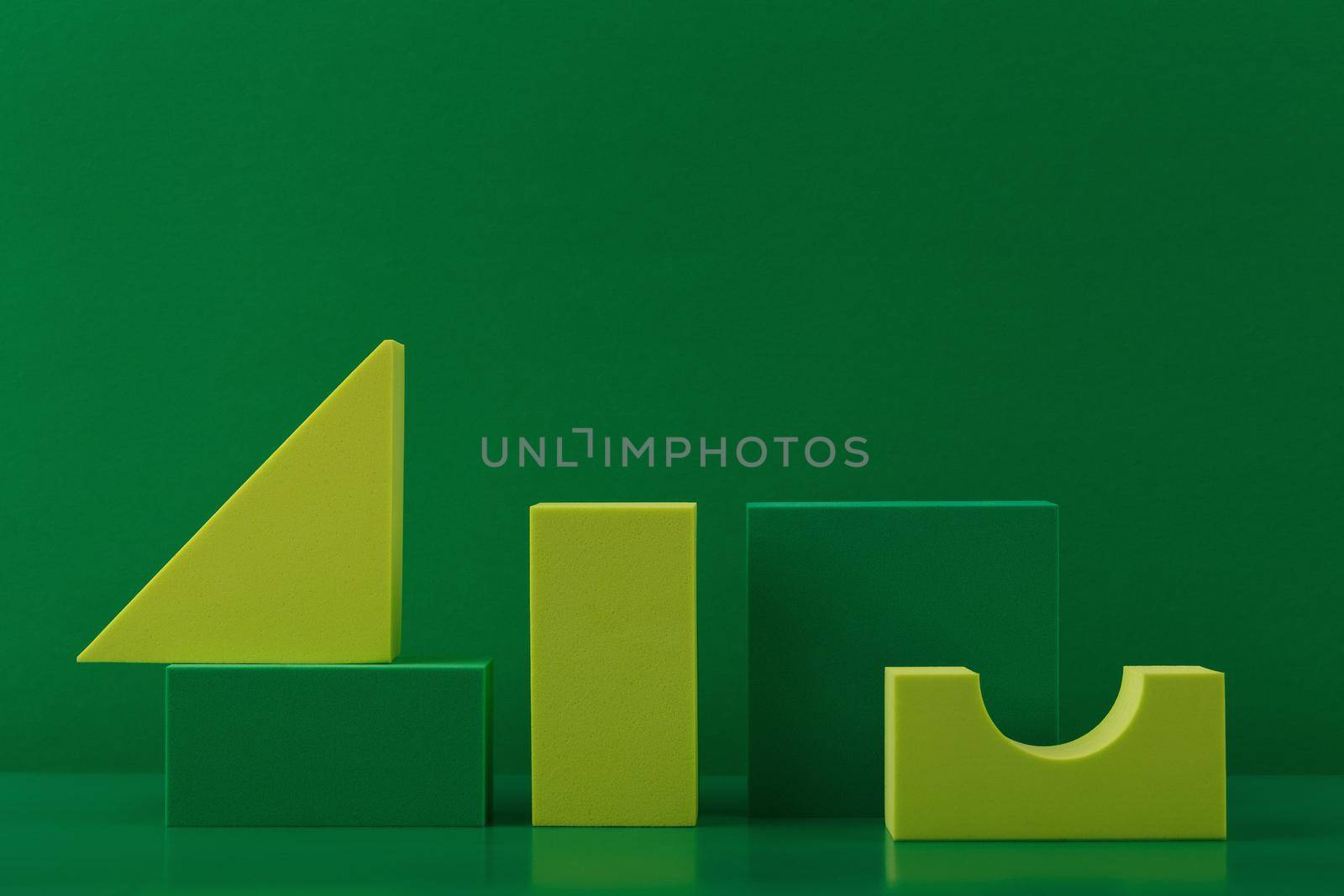 Abstract geometric composition with various green and yellow figures against dark green background with space for text. High quality photo