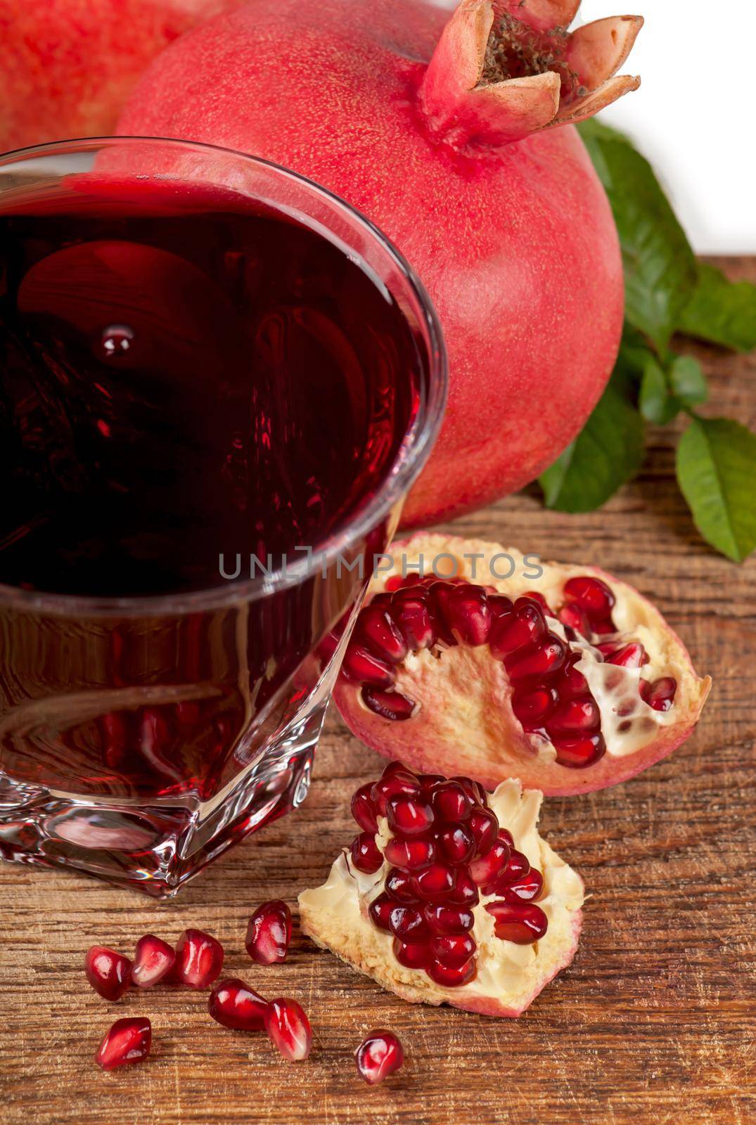 Garnet juice in a glass and pomegranate on wooden boards, on natural fabric