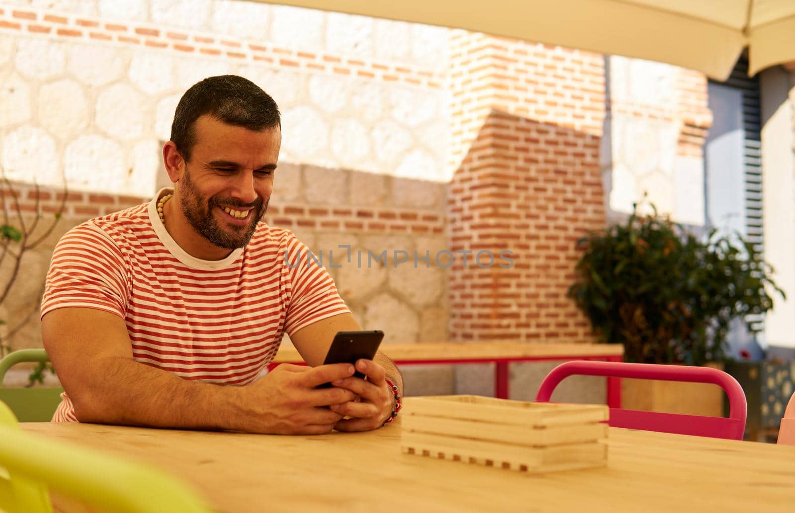 Man sitting on a terrace with his mobile phone in summer