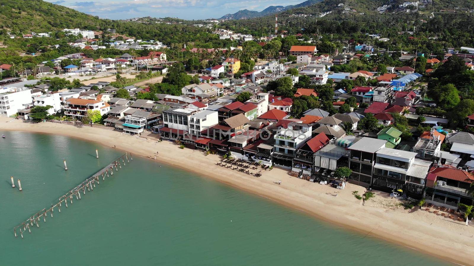 Fisherman village on seashore. Aerial view of typical touristic place on Ko Samui island with souvenir shops and walking street on sunny day. Architecture in asia, local settlement drone view by DogoraSun