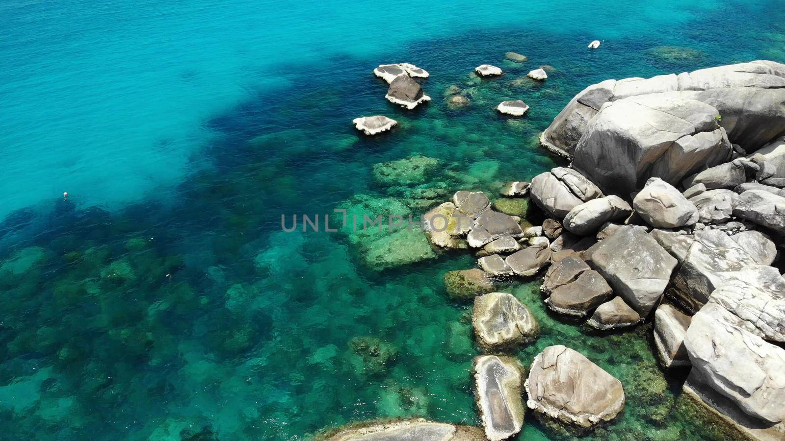 Calm sea water near stones. Peaceful blue sea water and gray boulders in perfect place for snorkeling on Koh Tao Island on sunny day in Thailand. Natural background texture