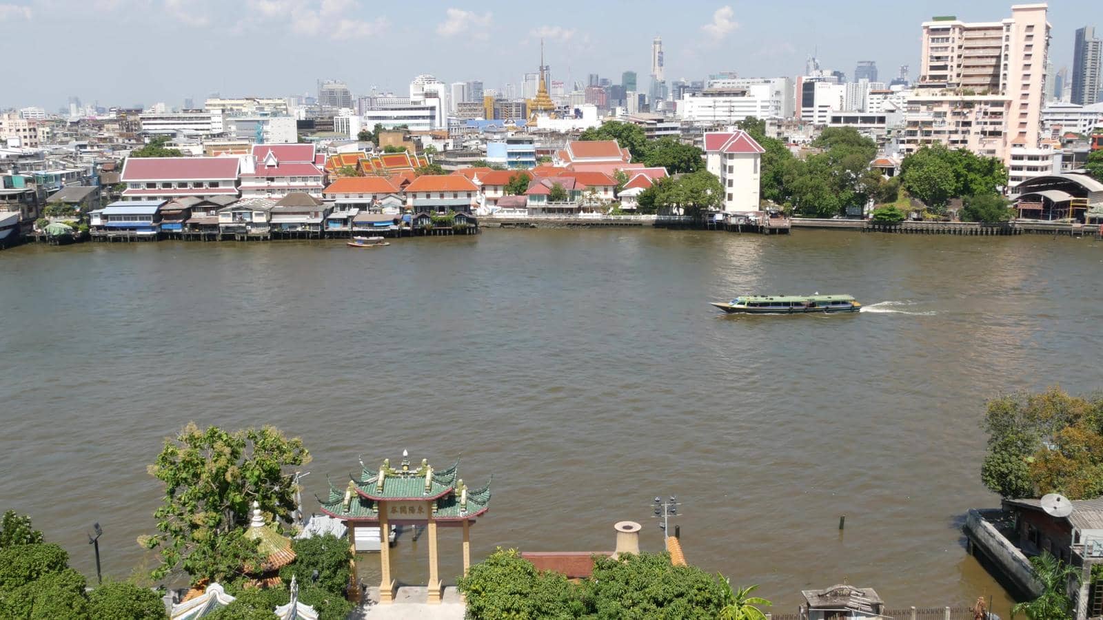 Oriental boat floating on river in Krungthep city. Modern transport vessel floating on calm Chao Praya river on sunny day in Bangkok near chinatown. Panorama by DogoraSun