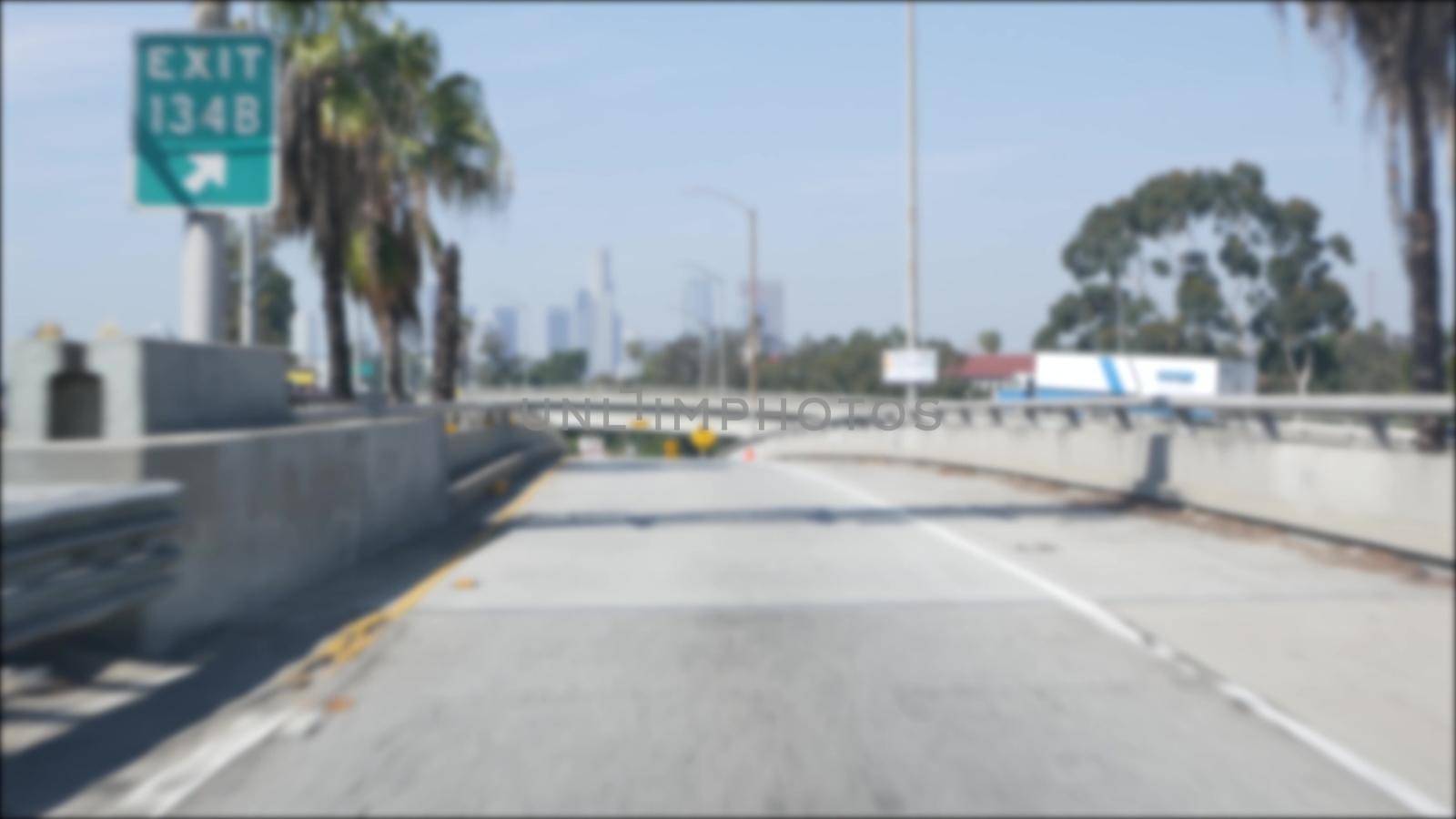 Driving on intercity freeway in Los Angeles, California USA. Defocused view from car thru glass windshield on busy interstate highway. Blurred suburb multiple lane driveway. Camera inside auto in LA.