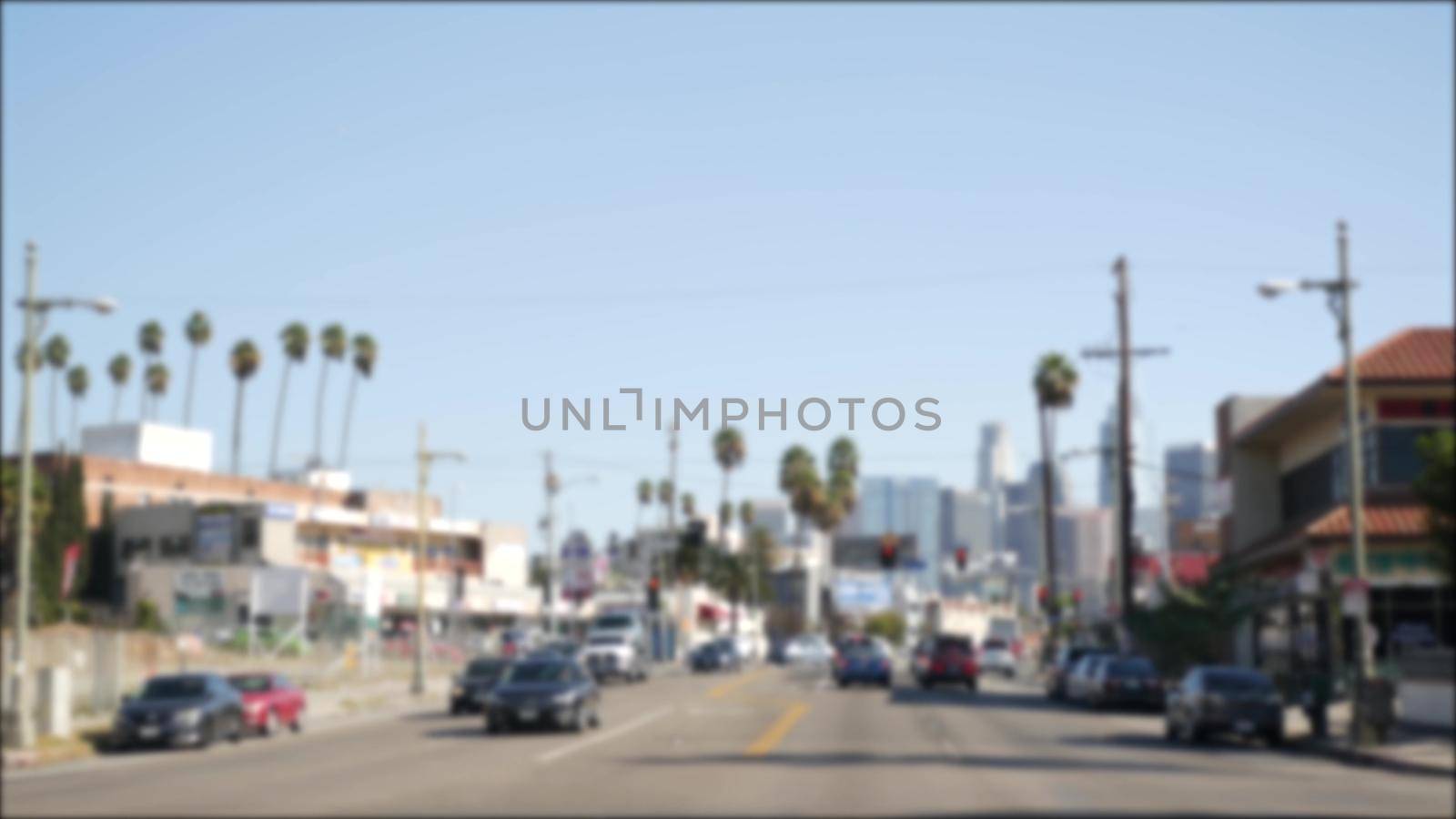 Driving on downtown streets of Los Angeles, California USA. Defocused view from car thru glass windshield on driveway. Blurred road with vehicles in Hollywood. Camera inside auto, LA city aesthetic.