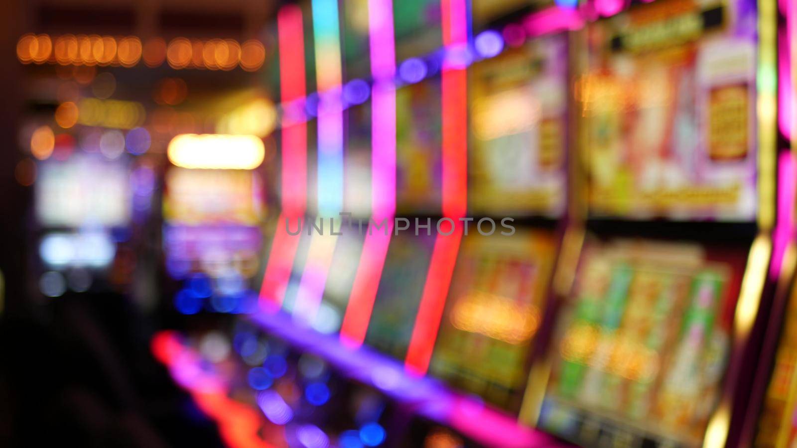 Defocused slot machines glow in casino on fabulous Las Vegas Strip, USA. Blurred gambling jackpot slots in hotel near Fremont street. Illuminated neon fruit machine for risk money playing and betting.