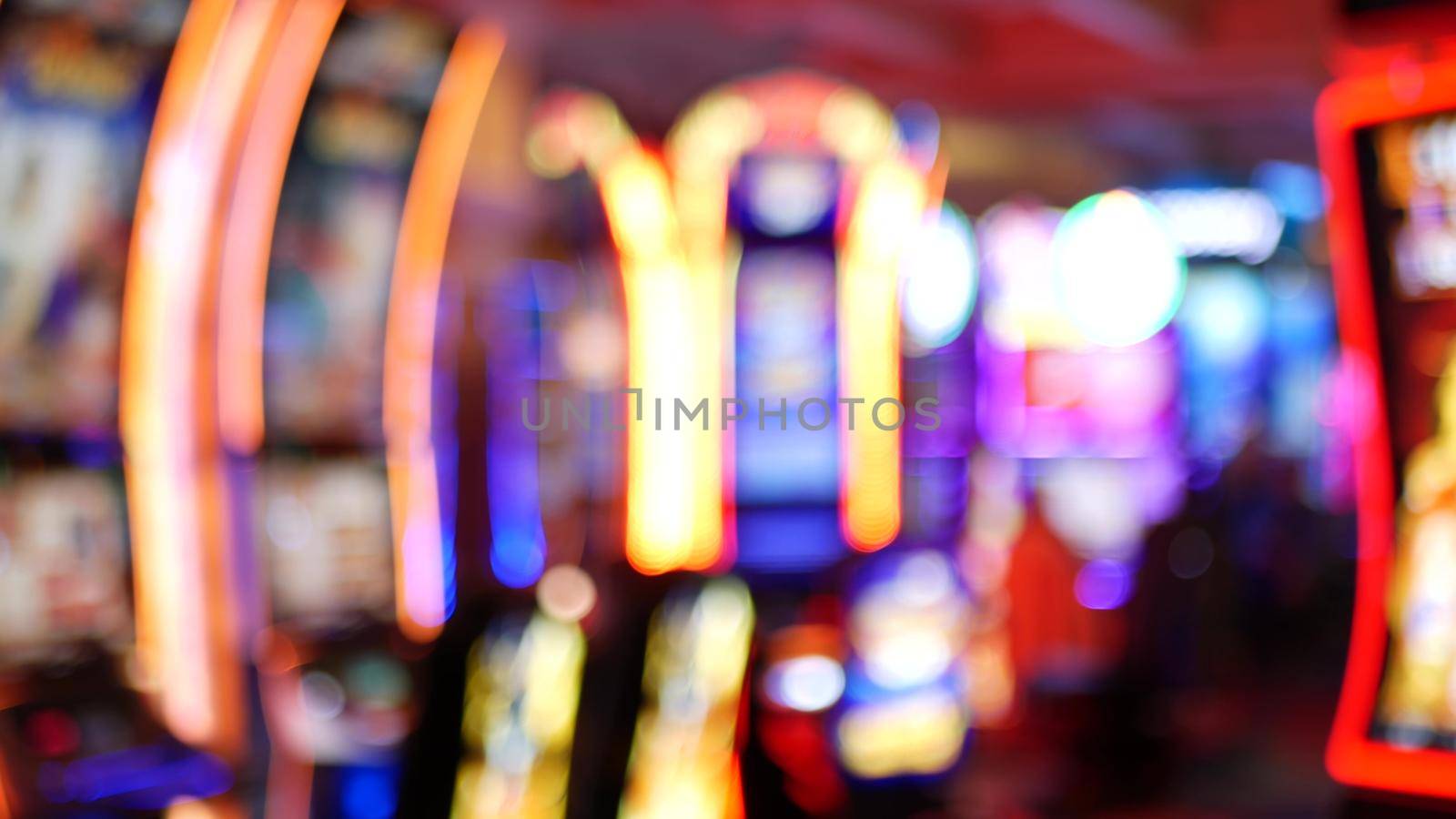 Defocused slot machines glow in casino on fabulous Las Vegas Strip, USA. Blurred gambling jackpot slots in hotel near Fremont street. Illuminated neon fruit machine for risk money playing and betting.