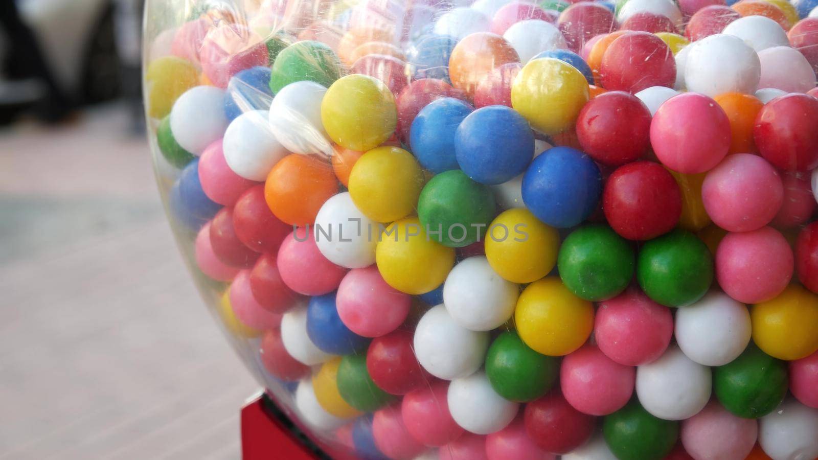 Colorful gumballs in classic vending machine, USA. Multi colored buble gums, coin operated retro dispenser. Chewing gum candies as symbol of childhood and summertime. Mixed sweets in vintage automate.