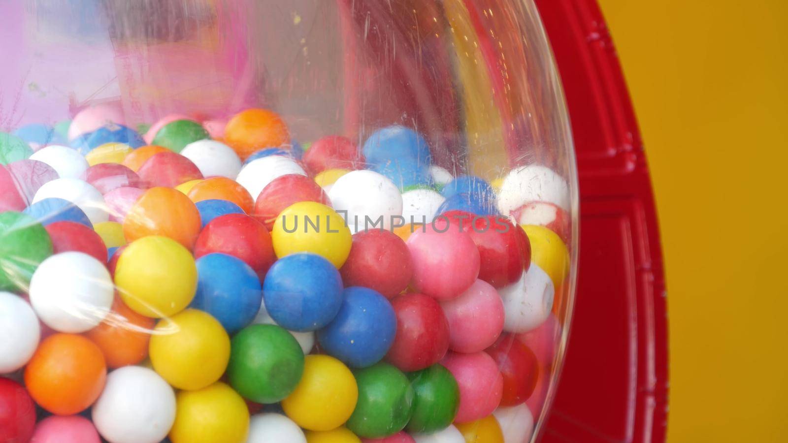 Colorful gumballs in classic vending machine, USA. Multi colored buble gums, coin operated retro dispenser. Chewing gum candies as symbol of childhood and summertime. Mixed sweets in vintage automate.