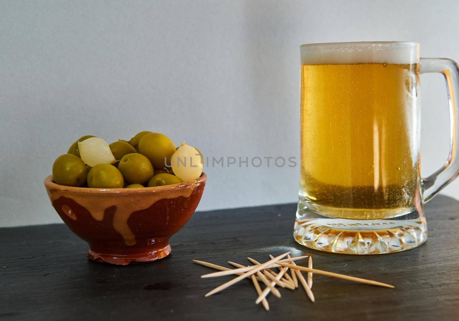 Beer with olives and potatoes with chopsticks on a black base