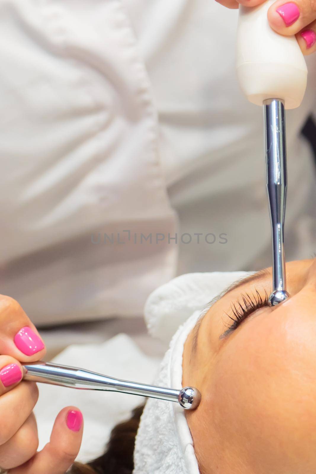 The girl is undergoing a procedure in a beauty salon. Anti-aging treatment with microcurrent drugs