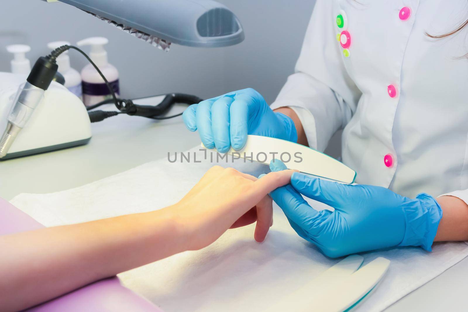 In a beauty salon, a woman is given a manicure using a nail file. Close-up.