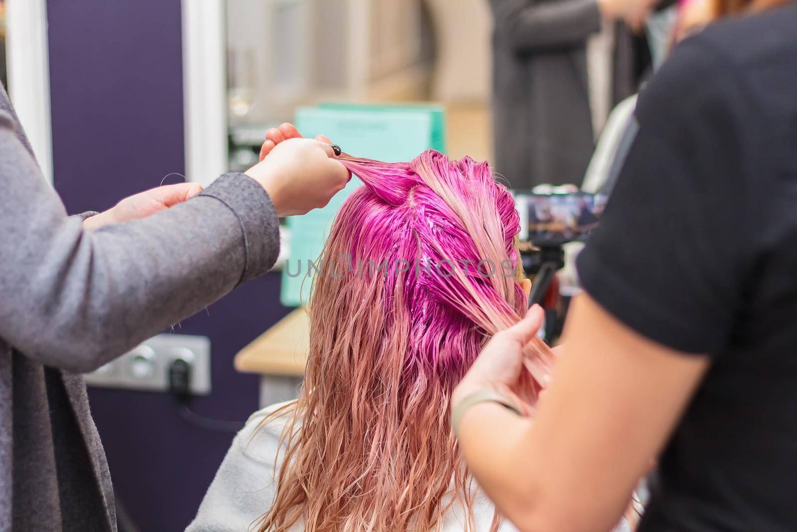 Hair dyeing for a girl in a beauty salon, long hair pink. Hair care