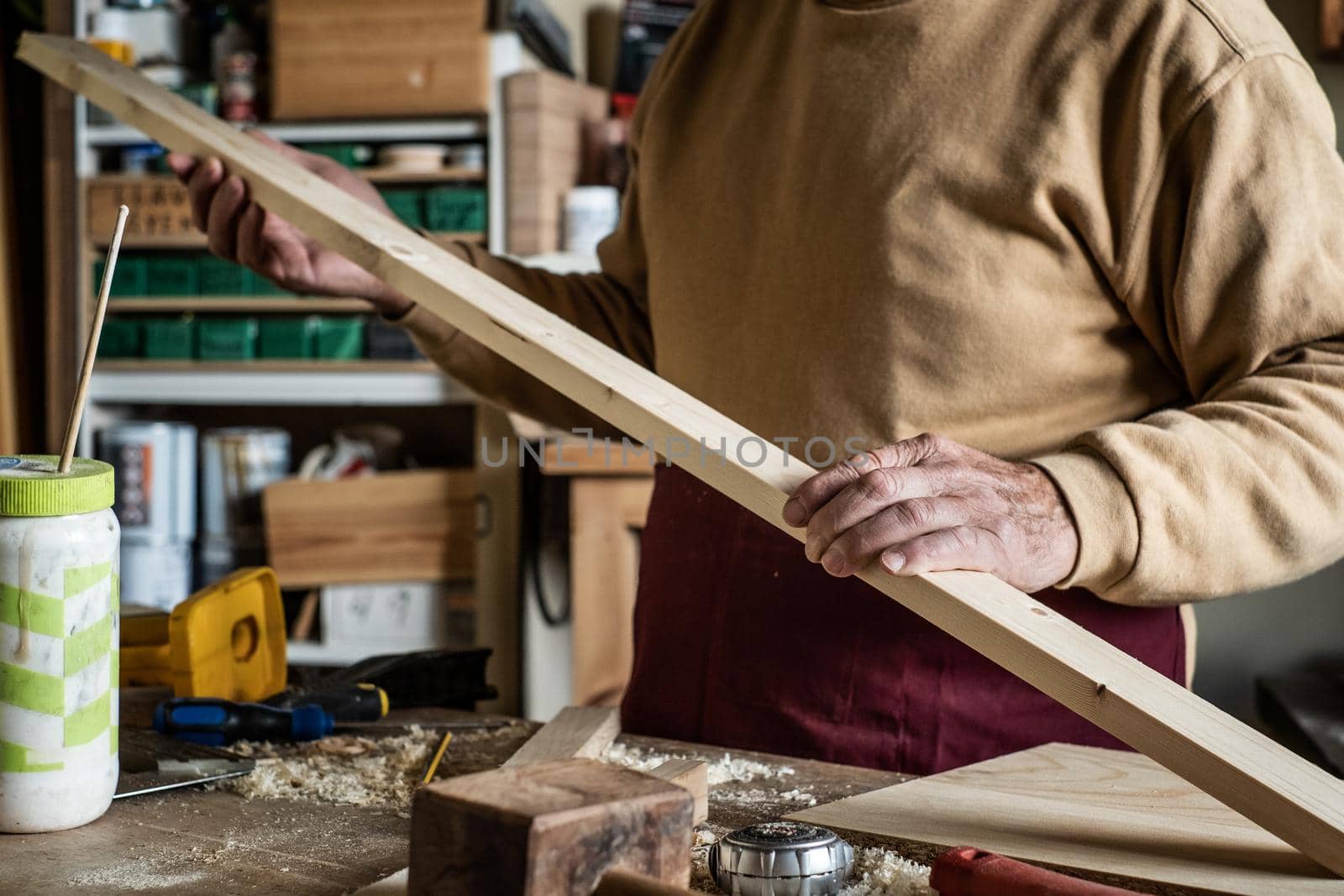 Carpenter looking at a wooden plank in a carpentry