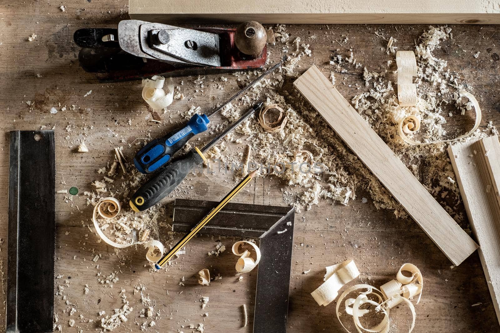 Workbench with a variety of hand tools in a woodworking or cabinetmaking workshop including chisels, screwdrivers, tape measure, pencil, ruler