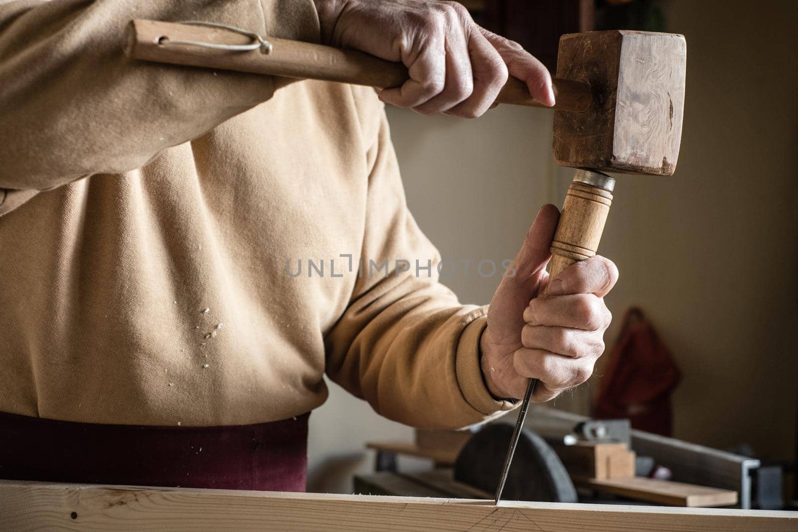 Carpenter working with a wooden hammer and a gouge