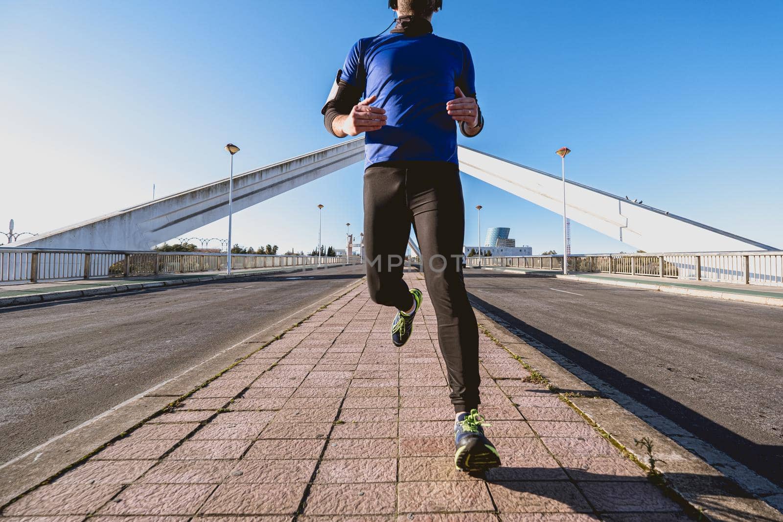 young man running down the street in front of a bridge