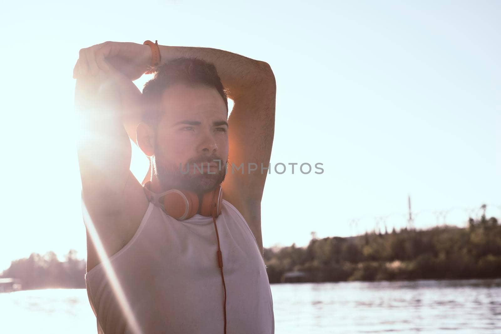 young man stretching out his arms with headphones on.