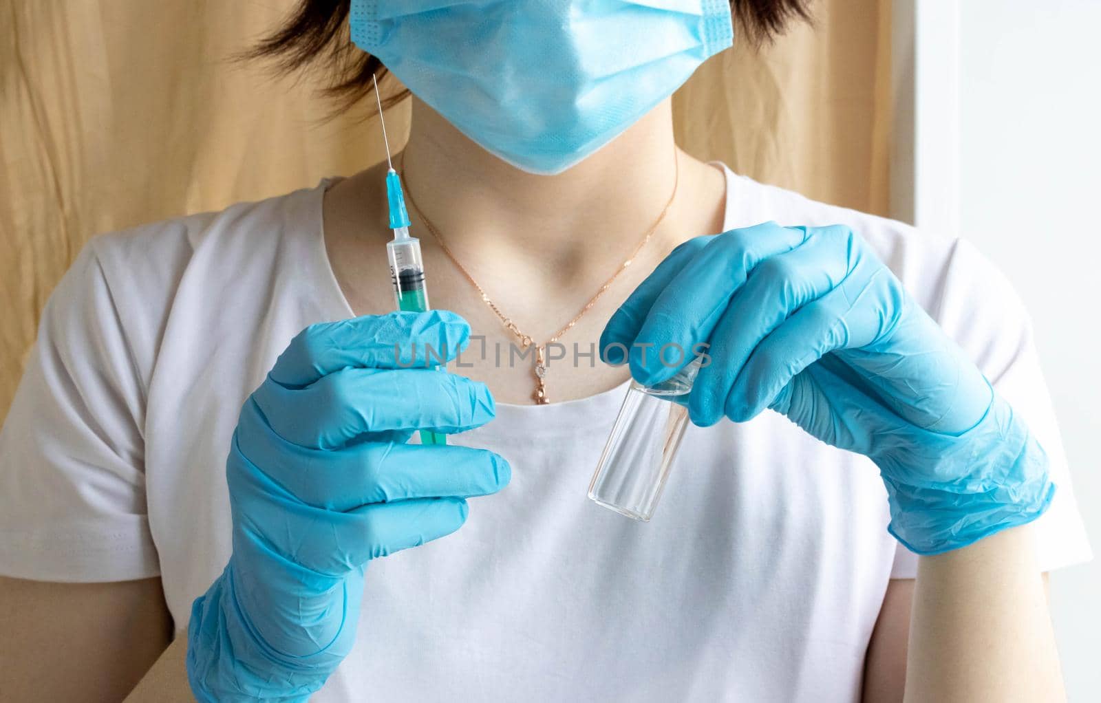 Nurse holds a syringe with a vaccine in her hand. Liquid in a syringe. Vaccination and healthcare. Medical concept. Doctor in gloves and a protective mask.
