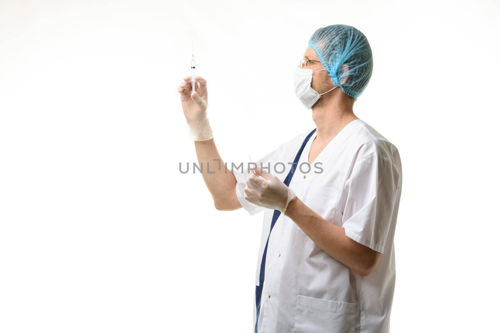 Surgeon holds a syringe in his hands and releases air bubbles from it, isolated on white background