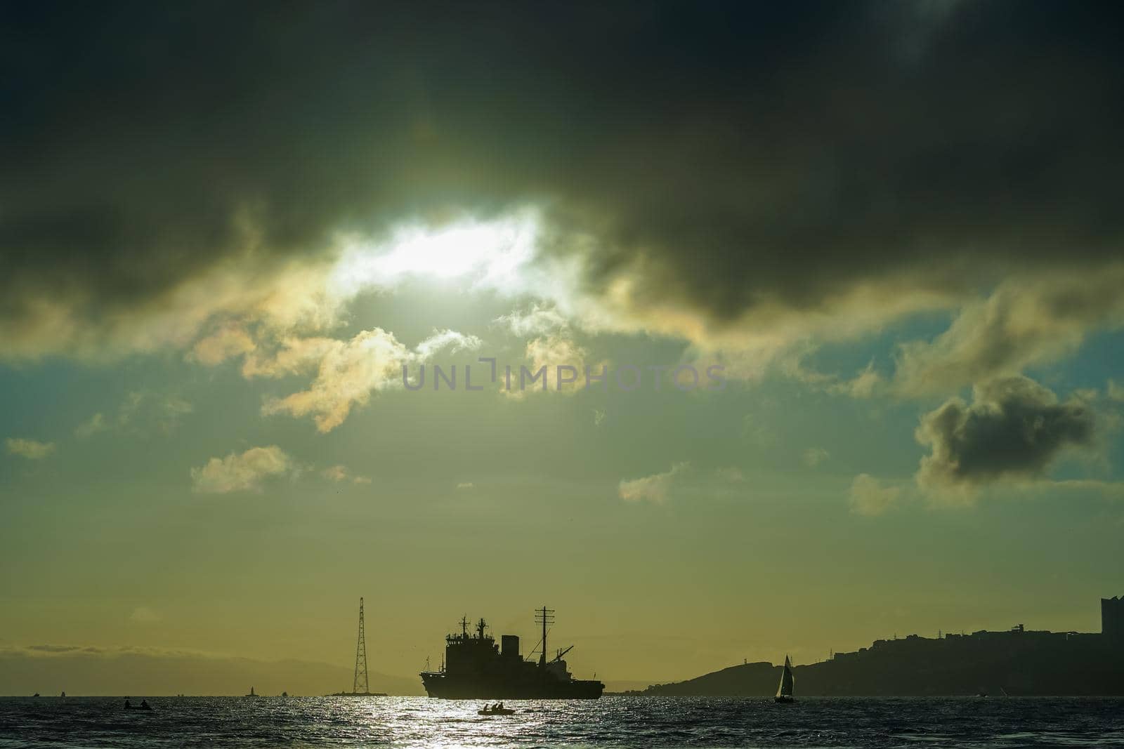 Seascape with a view of the silhouette of the city and the ship on the background of the sunset. Vladivostok, Russia
