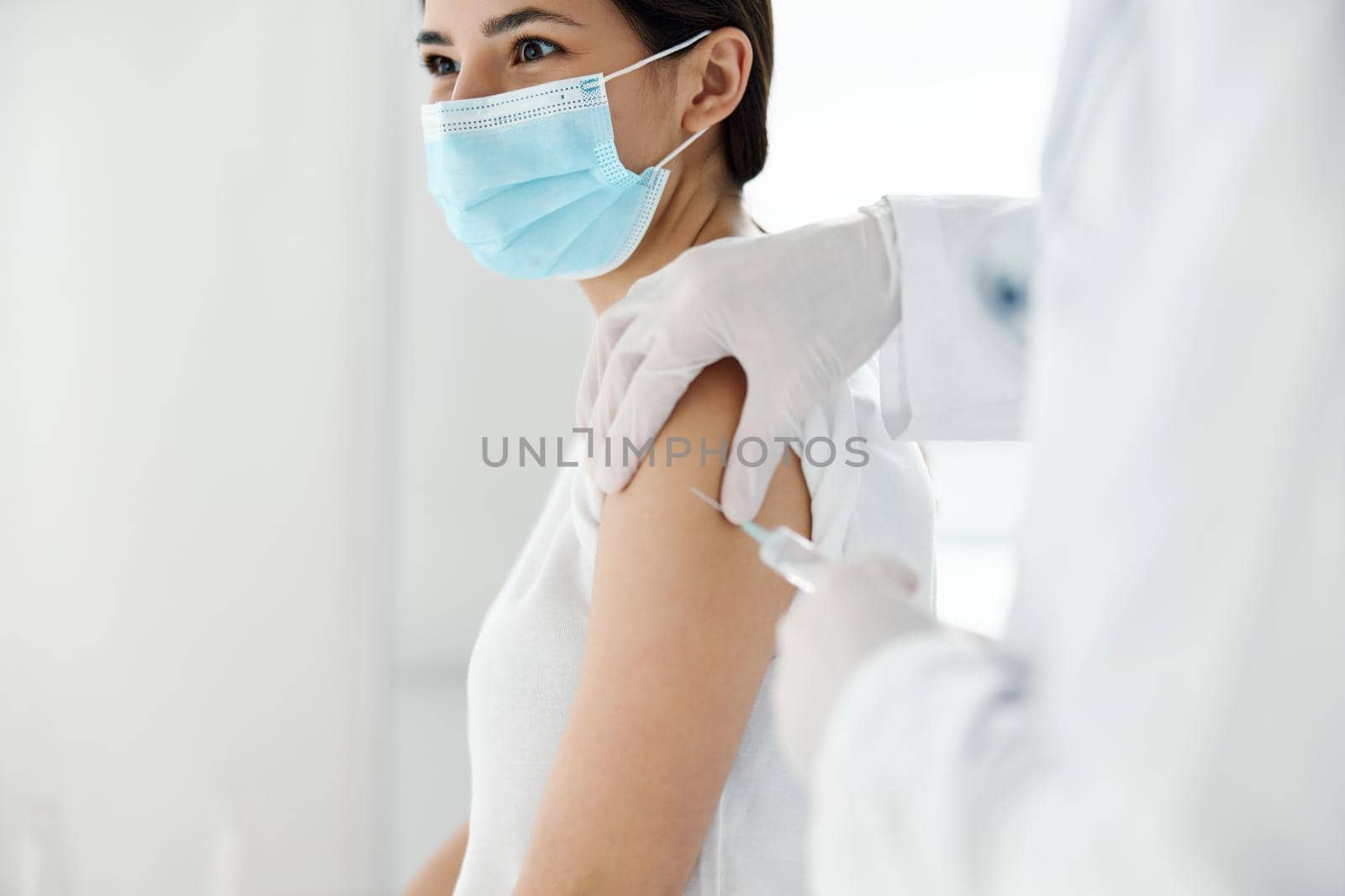 doctor in protective gloves injects a vaccine into the shoulder of a woman patient covid vaccination by SHOTPRIME