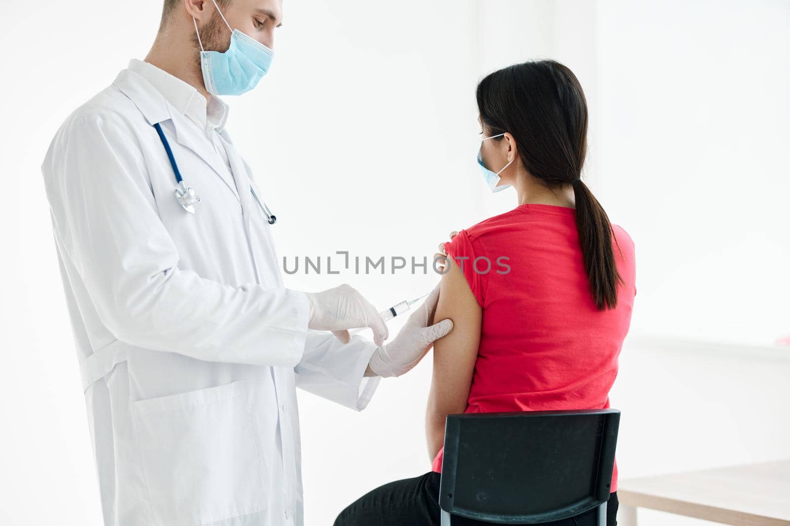 male doctor with a syringe in his hands make an injection in the patient's shoulder vaccination by SHOTPRIME