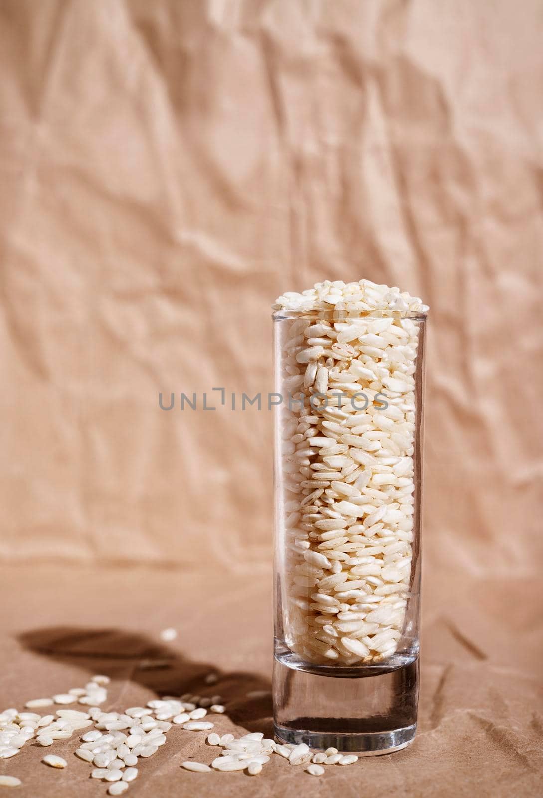 Uncooked white rice in long glass bowl  ,brown paper background