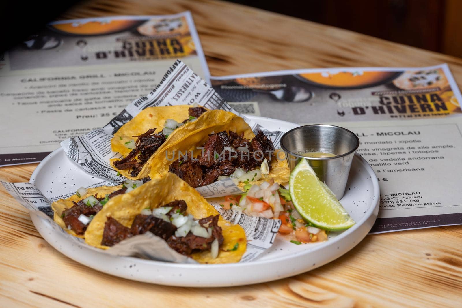 Two roast beef tacos with coriander and onion in corn tortillas.