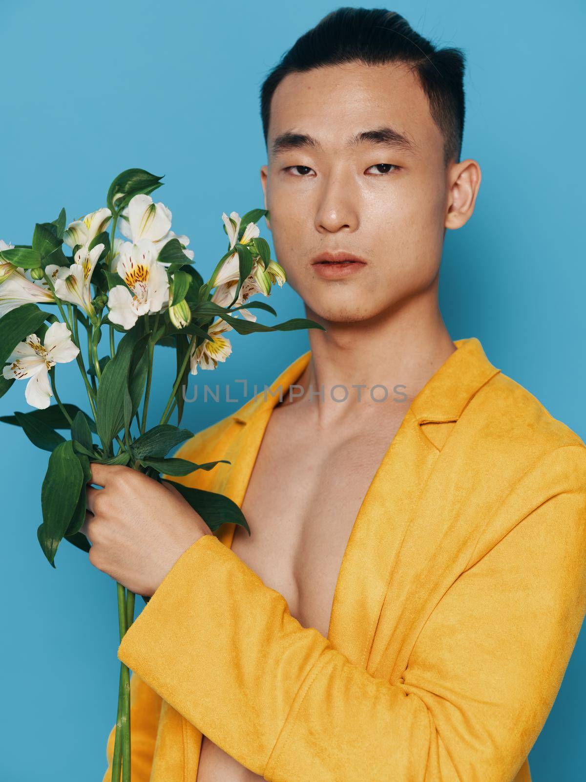 A romantic guy in an unbuttoned coat, Asian appearance and a bouquet of flowers in his hand by SHOTPRIME