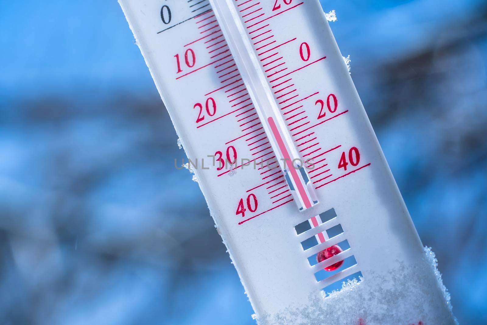 The thermometer lies on the snow in winter showing a negative temperature. Meteorological conditions in a harsh climate in winter with low air and ambient temperatures.Freeze in wintertime by YevgeniySam