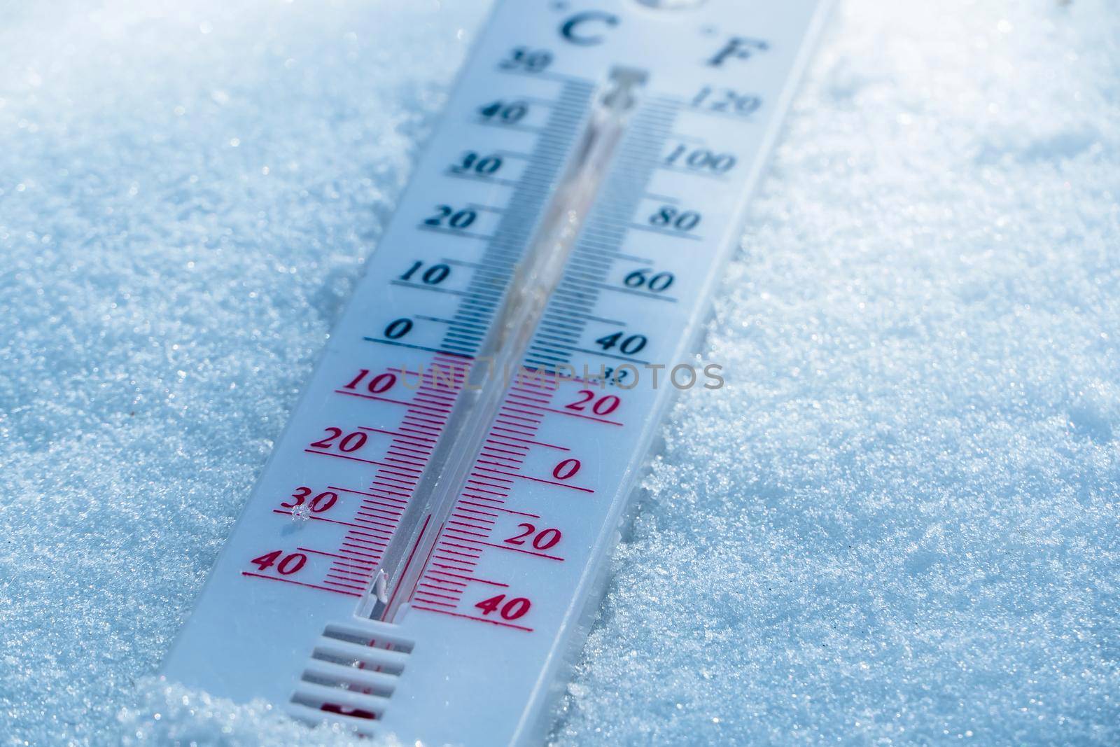 The thermometer lies on the snow in winter showing a negative temperature. Meteorological conditions in a harsh climate in winter with low air and ambient temperatures.Freeze in wintertime