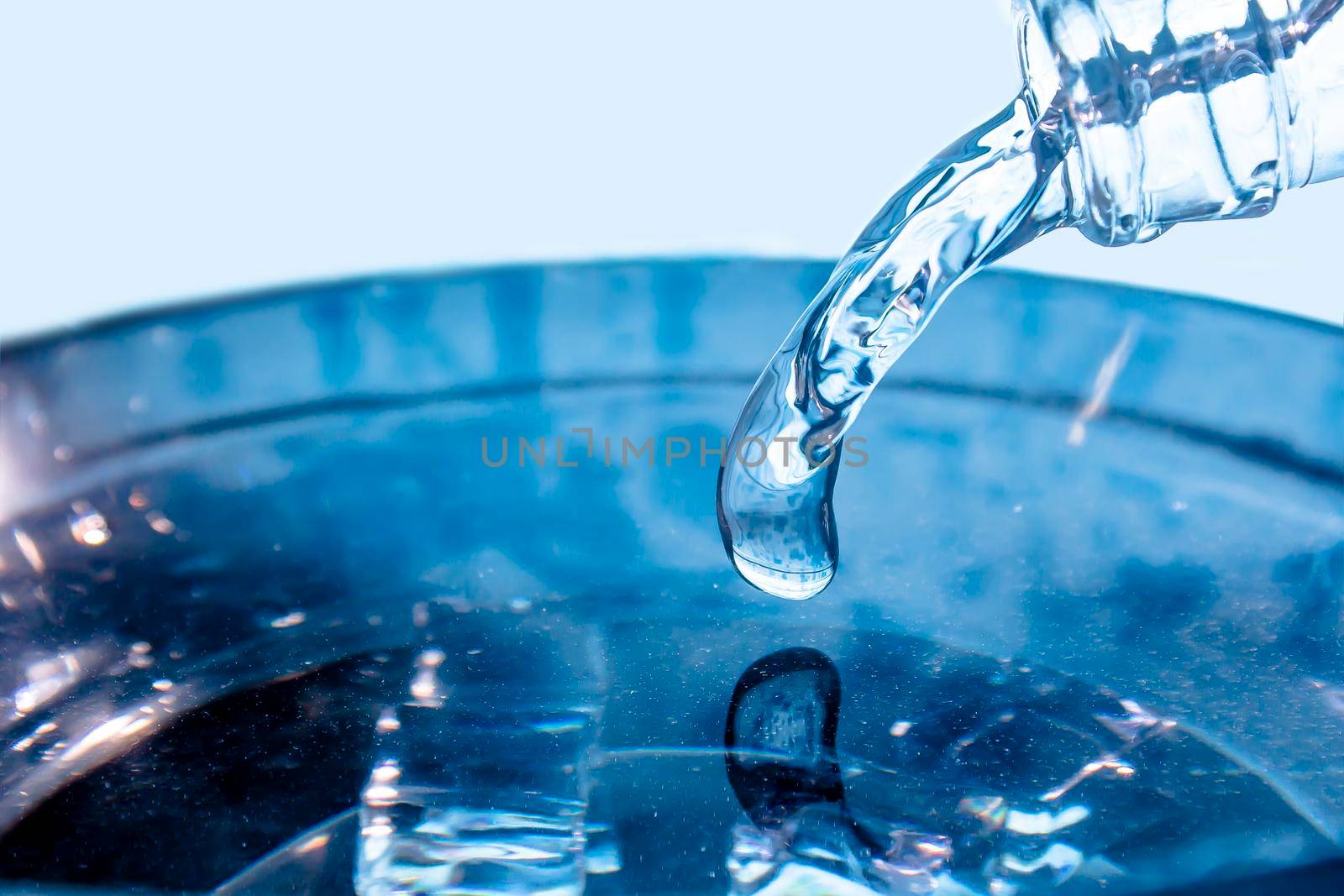 A flowing stream of blue water.A stream of blue water pours from the neck of a glass bottle.Frozen water drop photographed at high speed.Slow dripping of liquid with air bubbles.Frozen liquid splashes