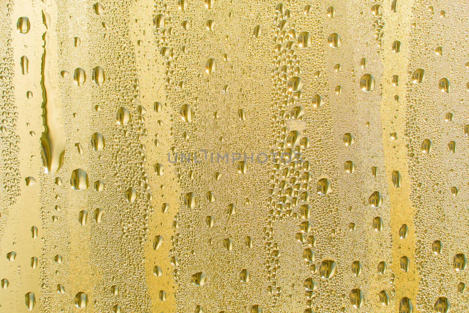 Abstract background ornament with golden water drops.Raindrops are golden in color.Sparkling shiny water surface on the glass.Water drops in the form of balls or spheres.Colored raindrops by YevgeniySam