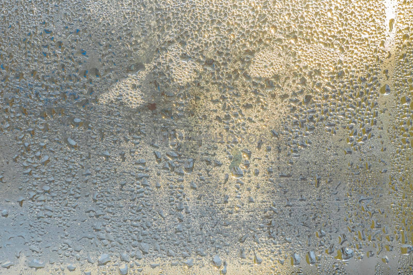 Raindrops on the glass in rainy weather.The glittering, shiny surface of water on glass.Water drops in the form of balls or spheres.Grey raindrops background. Abstract backgrounds ornament with water by YevgeniySam