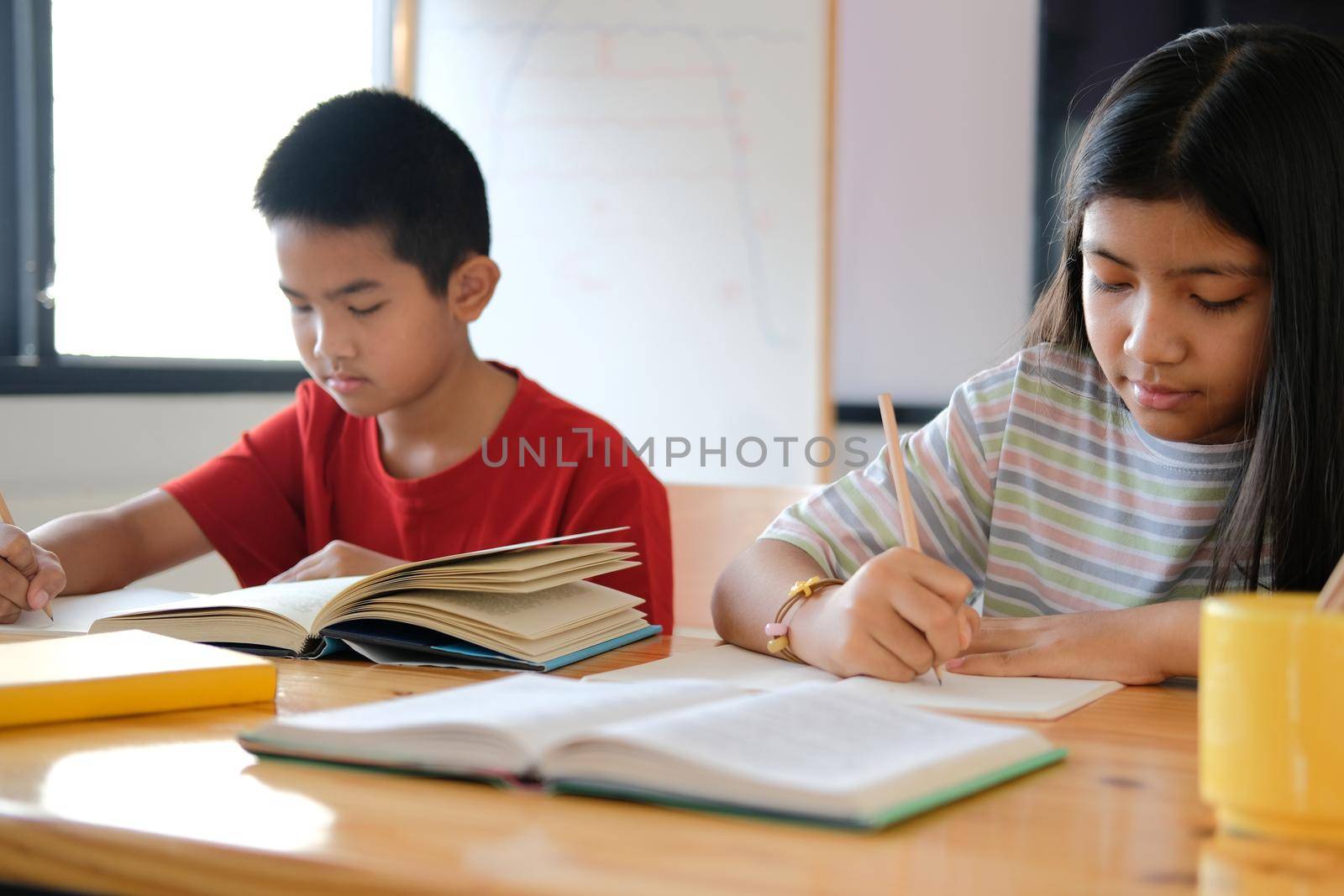 asian boy girl student studying writing notes doing homework in library. learning education at school