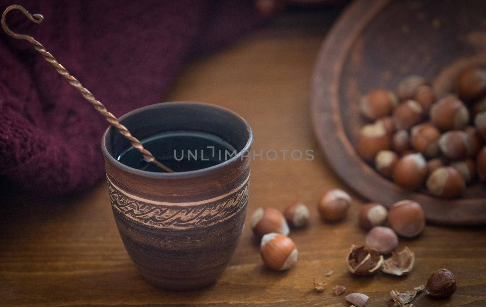 Dark background with a hot drink in a ceramic Cup and the scattered nuts hazelnuts on a wooden surface.