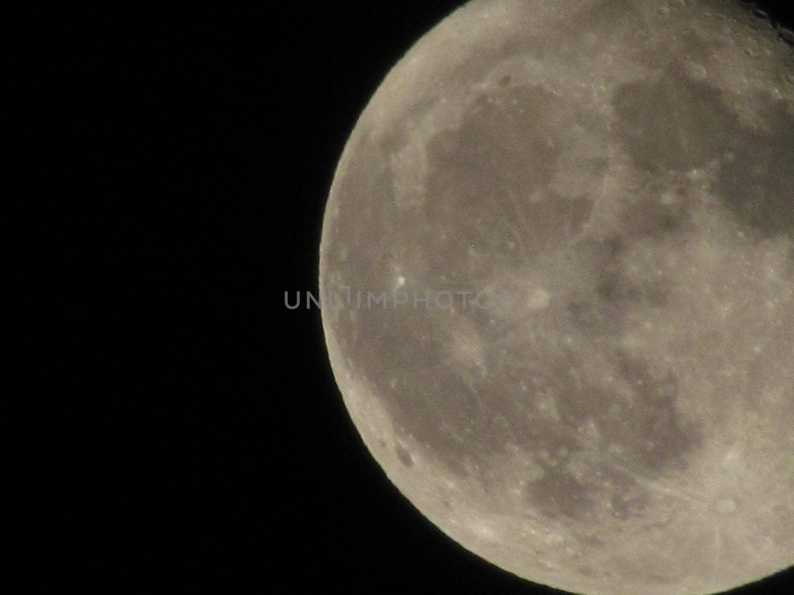 Earth's Moon Glowing On Black Background. The Moon close-up on a black night sky shot through a telephoto camera.