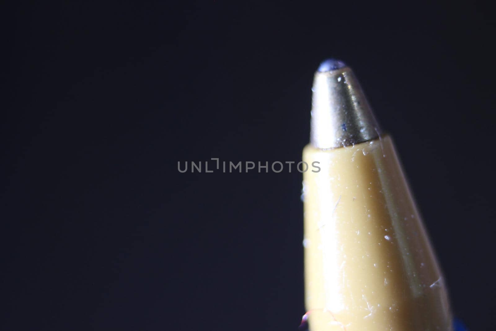 Macro photo of ballpoint pen tip with dark grey background. Extreme macro image of metal ballpoint pen on grey background.