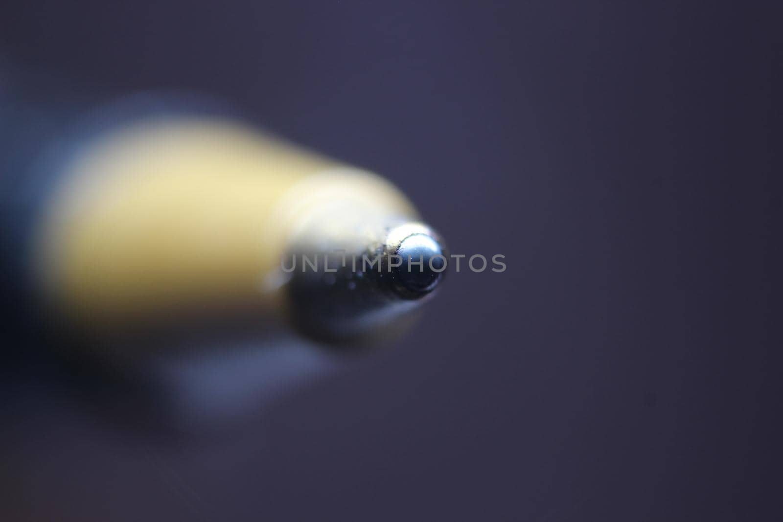 Macro photo of ballpoint pen tip with dark grey background. Extreme macro image of metal ballpoint pen on grey background.