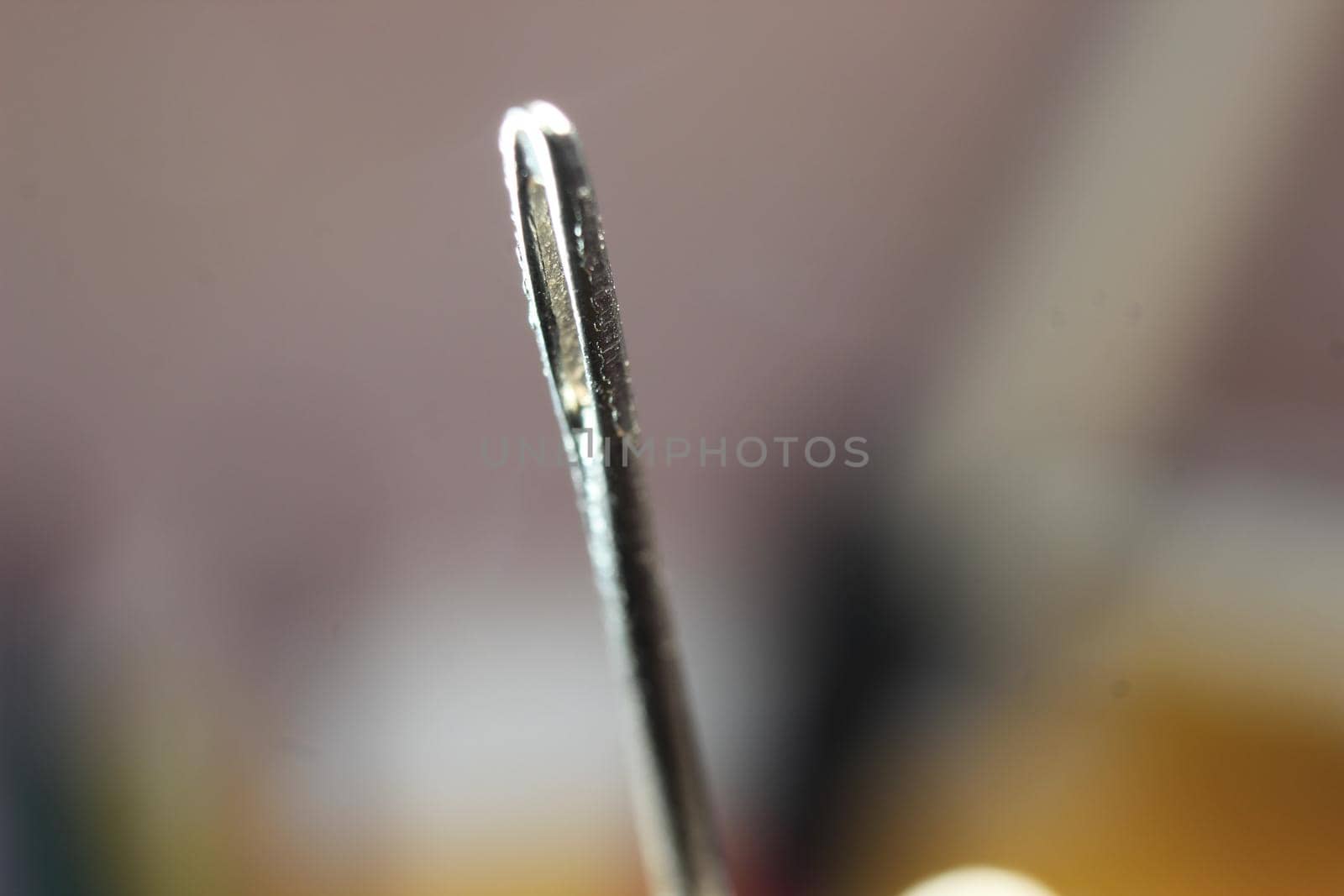 Macro photograph of sewing needle. Small needle with empty eyelet, isolated over the black background.