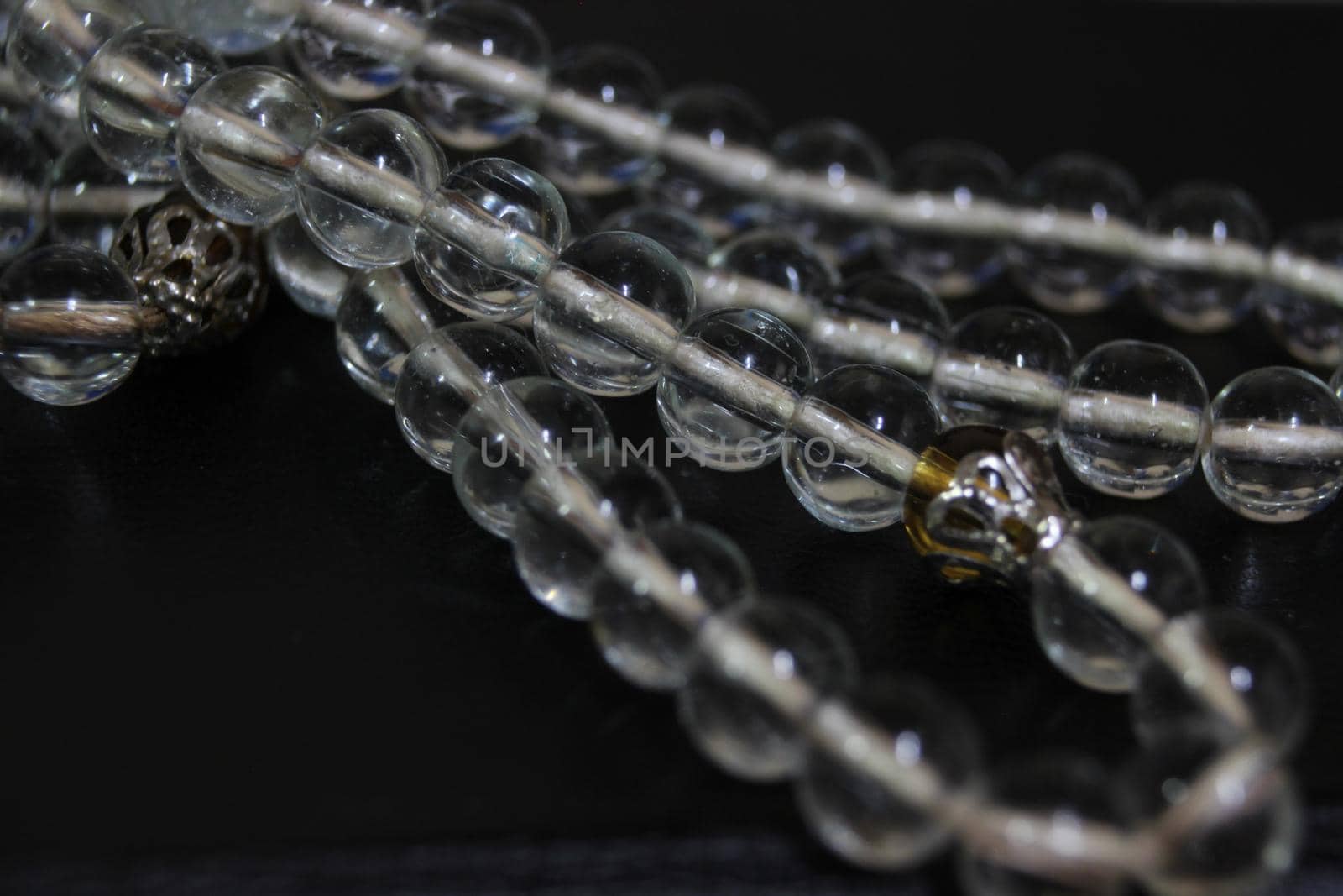 Macro photograph with selective focus of glass shiny prayer beads or rosary with copy space for text. Religion concept of ramadan or Eid for muslims.