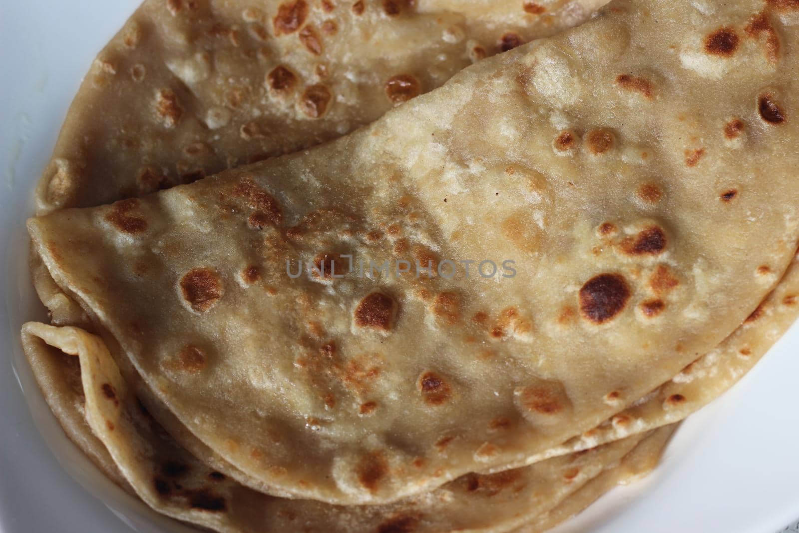 Closeup view of hand made plain bread in oil called paratha roti. by Photochowk