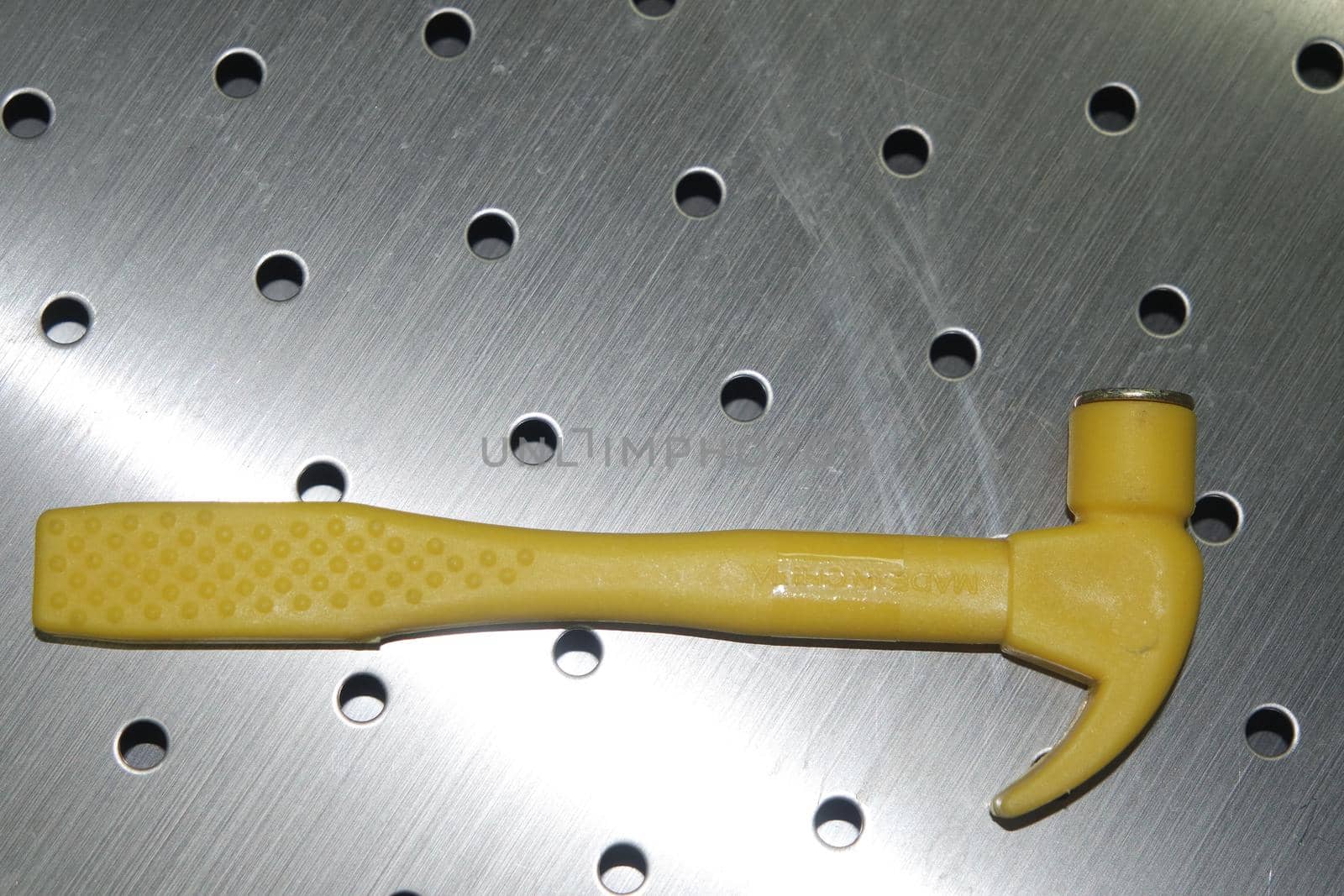 Selective focused, closeup view of toy hammer made from plastic placed on metal background