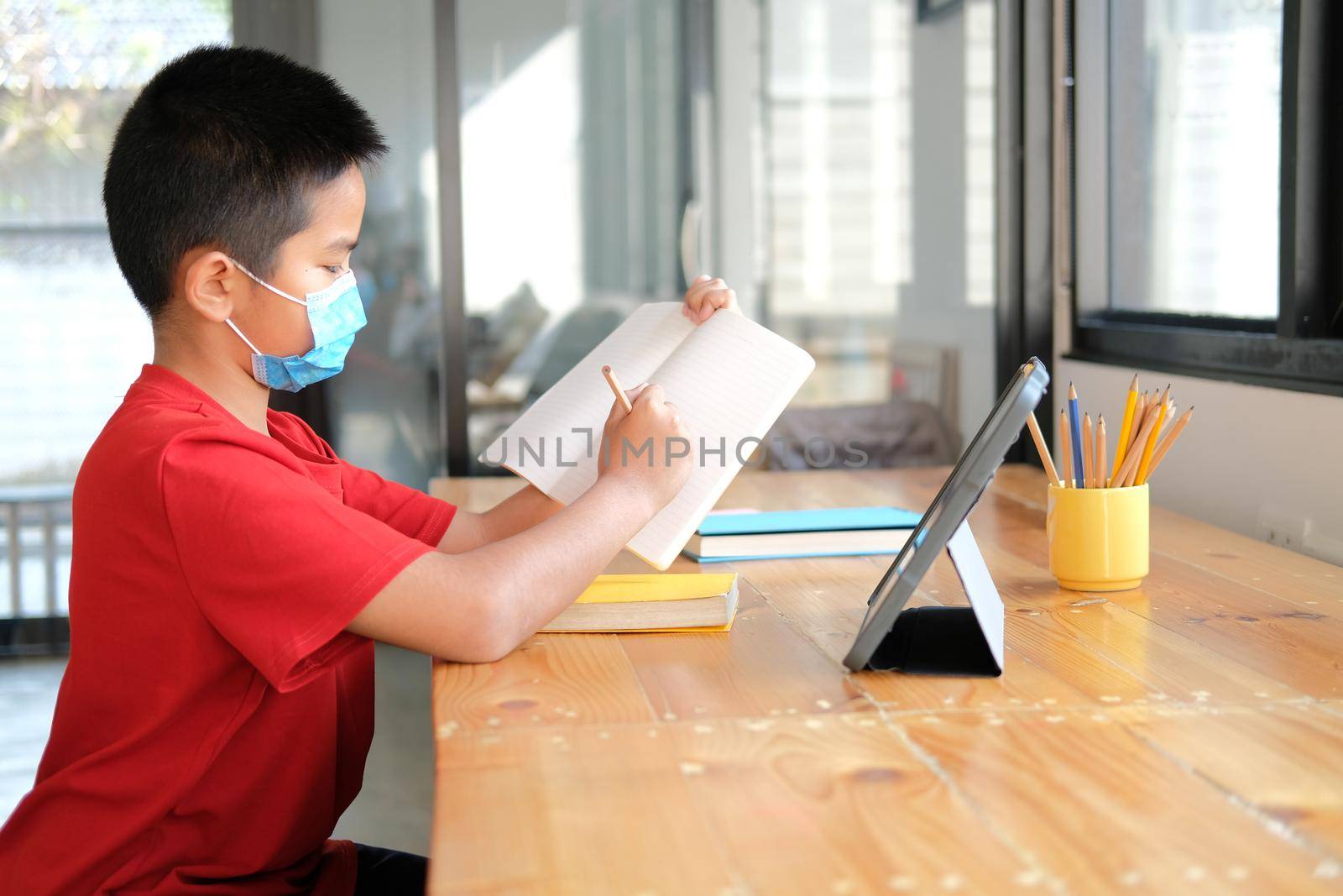 asian boy student wearing face mask studying learning lesson online. remote meeting distance education at home
