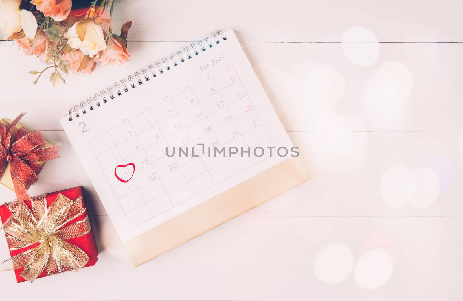 Calendar and flower with memo 14 February Valentine day on desk with blur bokeh background, reminder for surprise of love, romance and sweet, celebration and decoration, top view, holiday concept. by nnudoo