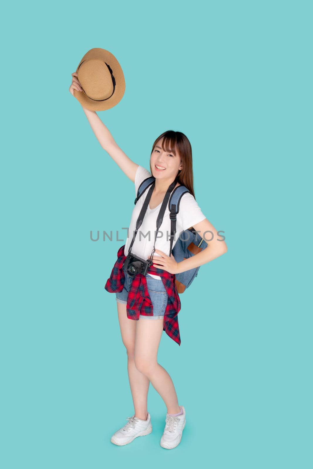 Beautiful portrait young asian woman smiling and holding hat and camera travel summer trip in vacation isolated on blue background, tourist asia girl cheerful journey with hobby in holiday concept.