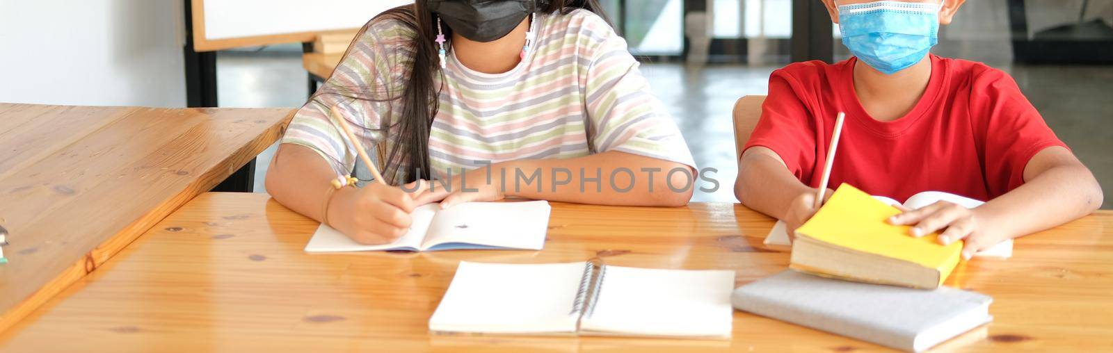 asian girl boy student wearing face mask studying writing notes doing homework in library. learning education at school