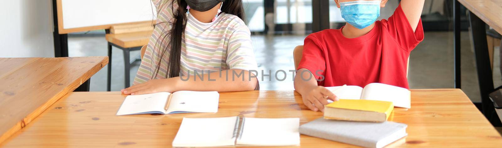 girl boy student wearing face mask studying raising hand in classroom. learning education at school by pp99