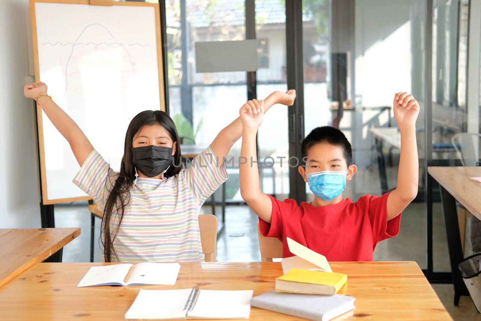 asian girl boy student wearing face mask stretching after studying hard feeling tired bored sleepy. children education
