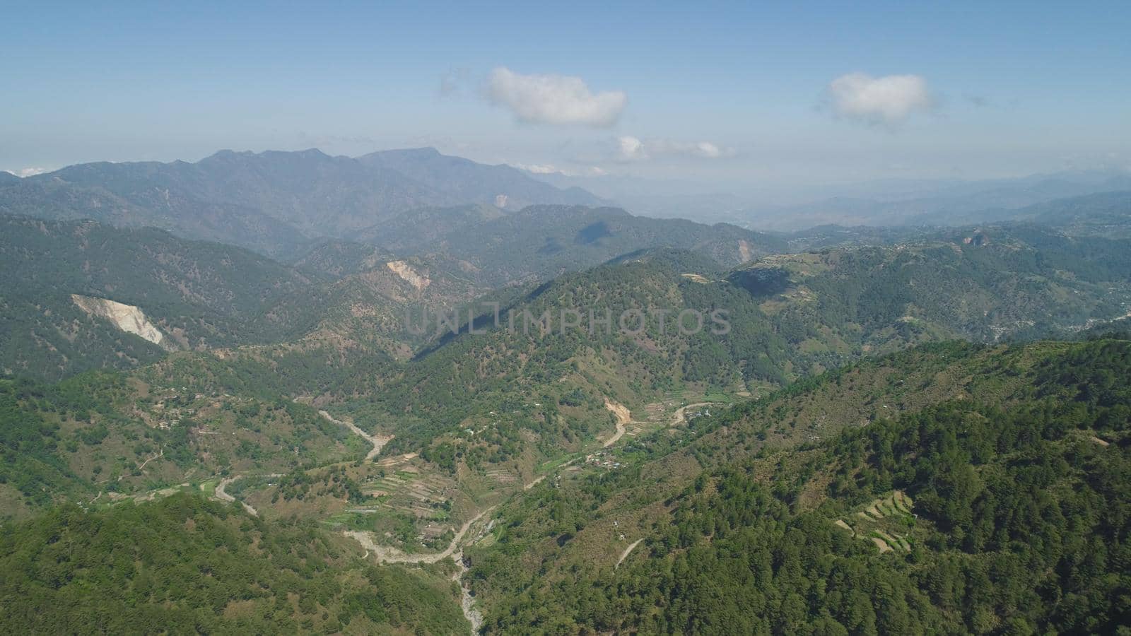 Aerial view of rice terraces and agricultural farm land on the slopes of mountains valley. Cultivation of agricultural products in mountain province. Mountains covered forest, trees. Cordillera region. Luzon, Philippines, Baguio province.